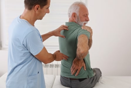 senior man with back pain. spine physical therapist and paient. chiropractic pain relief therapy